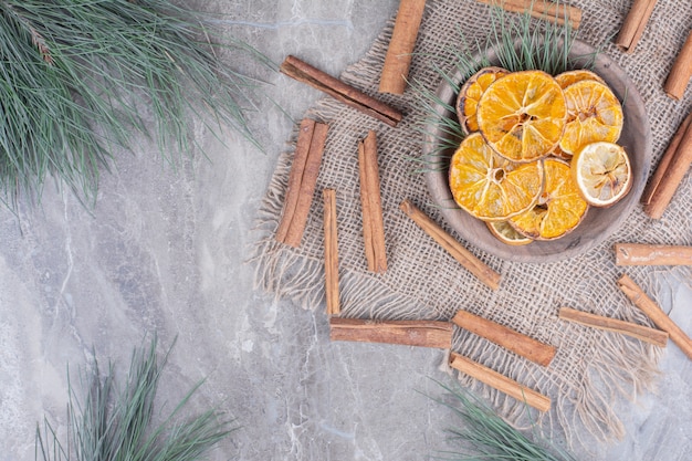 Orange slices in a wooden cup with cinnamon sticks around