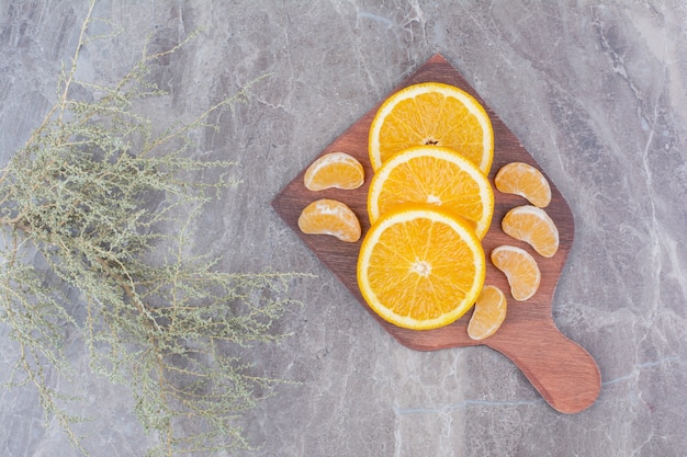 Free photo orange and tangerine slices on wooden board.