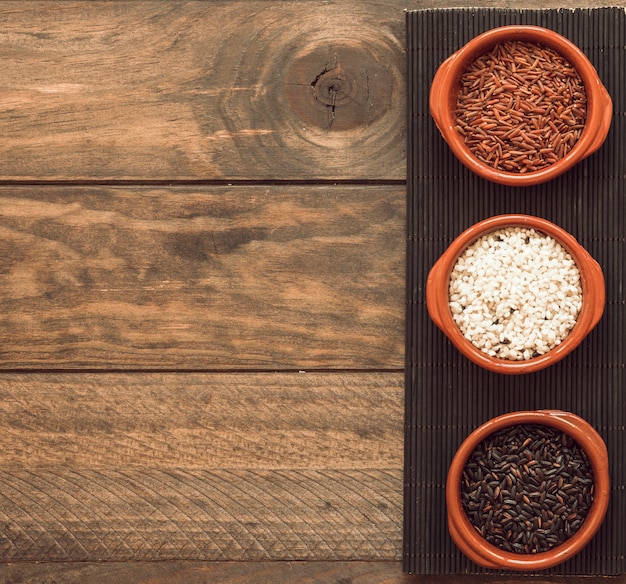 Organic brown and white rice grains bowls on tray over the wooden table