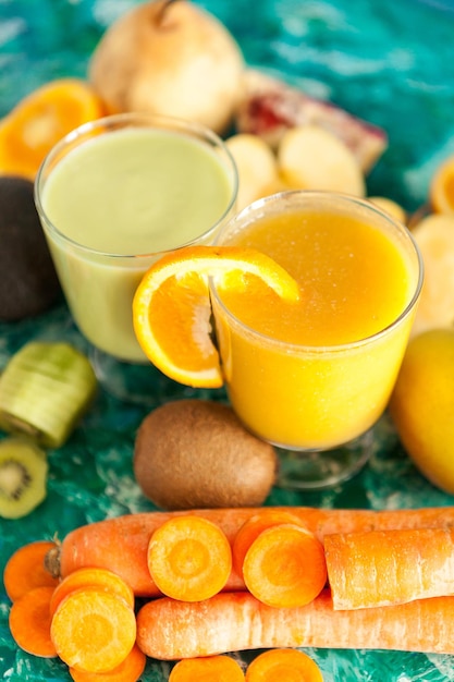 Organic fresh detox smoothies surrounded by fruits and vegetables on wooden background