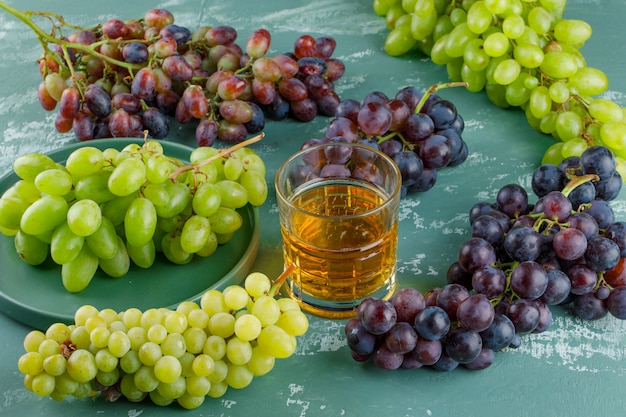 Organic grapes in a tray with drink high angle view on a plaster background