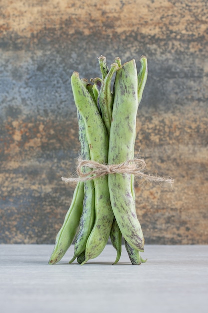 Organic green beans tied with rope on stone table. High quality photo