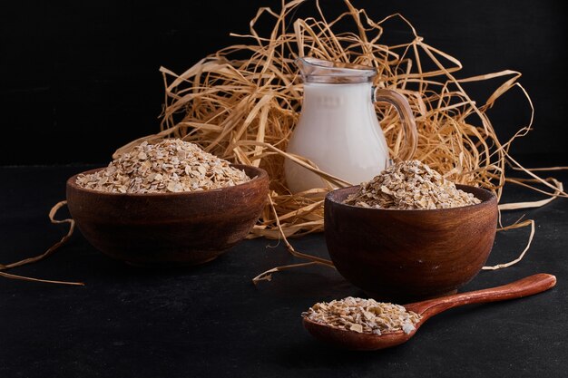 Organic mueslies in wooden cups and spoon with a jar of milk. 