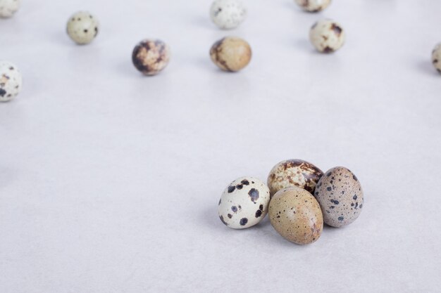 Organic quail eggs on white surface.