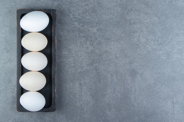 Organic raw eggs on black plate.