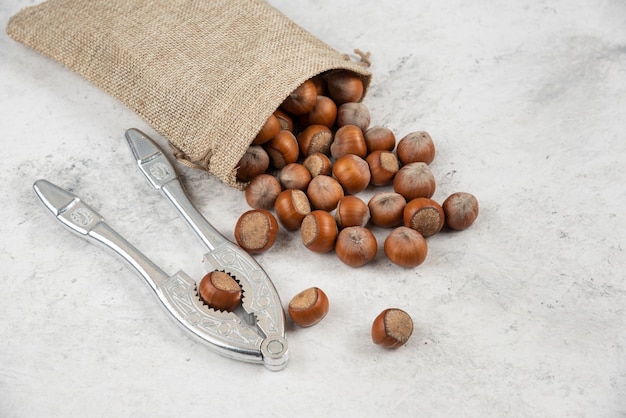 Free Photo organic shelled hazelnuts in burlap with nut cracking tool. 