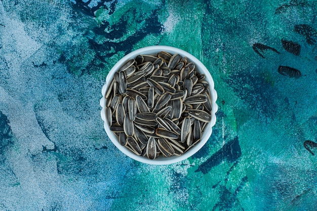 Free photo organic sunflower seed in a bowl, on the blue table.