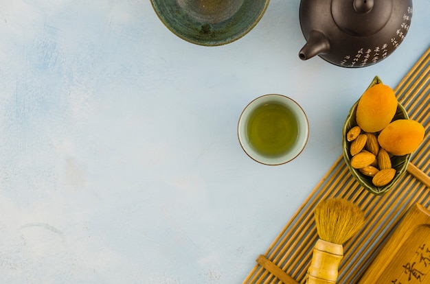 Free photo oriental tea set with brush and dried fruits on white backdrop