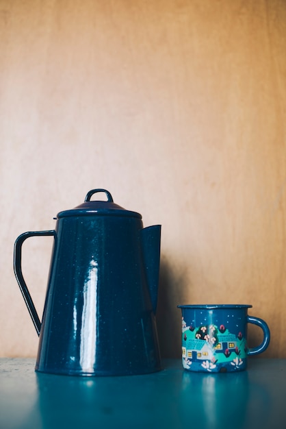 Free photo ornamental porcelain teapot and mug against wooden backdrop