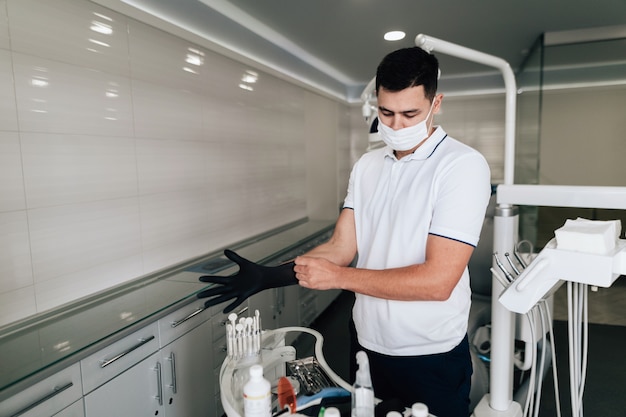 Orthodontist putting on surgical gloves in office