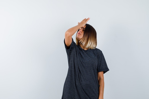 Free photo ortrait of young female holding hand on forehead in polo dress and looking forgetful front view