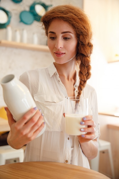 Free photo ortrait of a young redhead woman holding bottle with milk