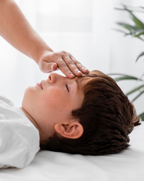 Osteopathist treating a kid by massaging his head