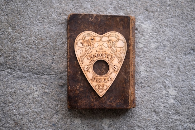 Free photo ouija board planchette on old book top view