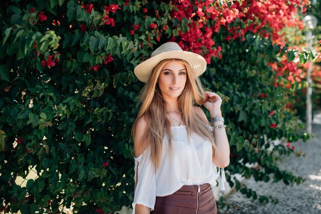 Outdoor close up portrait of young beautiful fashionable girl posing near blooming tree with flowers.