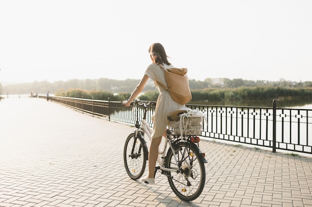 Outdoor portrait of attractive young brunette in a hat on a bicycle.