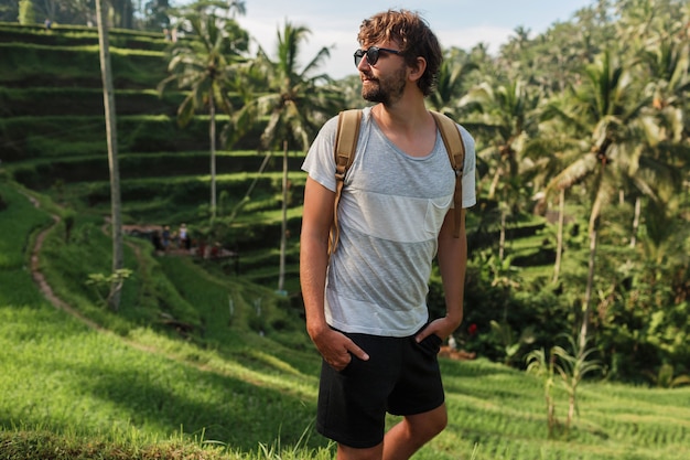 Free Photo outdoor portrait of handsome travel man with back pack walking on rise terrace in bali.