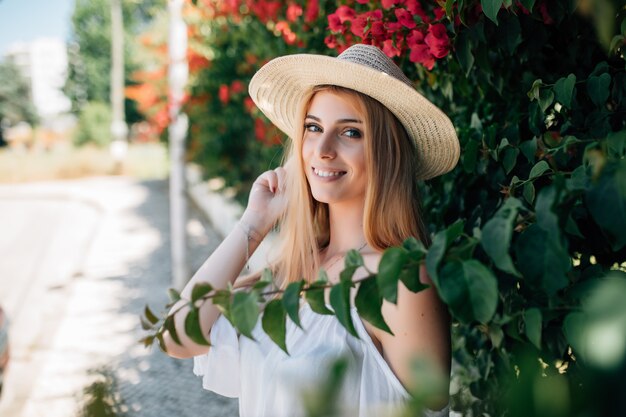 Outdoor portrait of young beautiful happy smiling lady posing near flowering tree. City lifestyle