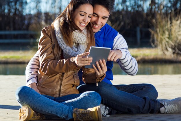 Outdoor portrait of young couple with digital tablet