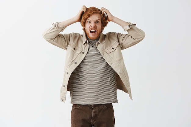 Free Photo outraged bearded redhead guy posing against the white wall