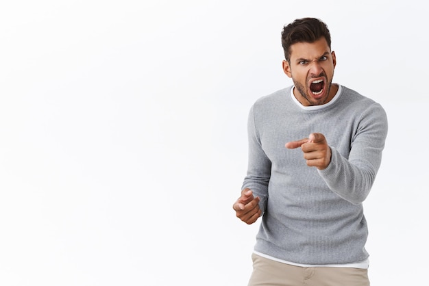 Free photo outraged handsome man with bad temper losing control over emotions distressed pointing camera and shouting accusations blame someone in anger and furious feelings standing white background