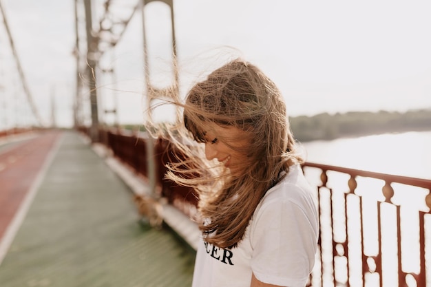 Outside portrait of of appealing girl smiling with wonderful happy emotions and covering face with flying hair