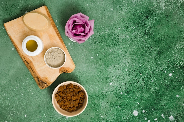 Free Photo oval herbal rose; oil; rhassoul clay; coffee powder and purple rose on green textured background