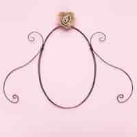 Free photo oval shape frame with artificial rose on pink backdrop