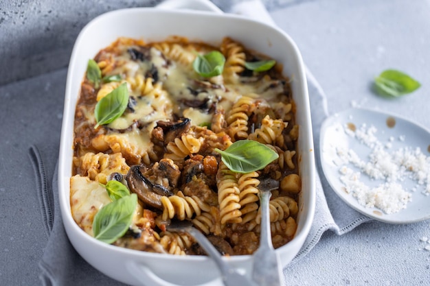 Free Photo oven baked pasta with vegetables meat and champignons in bowl closeup