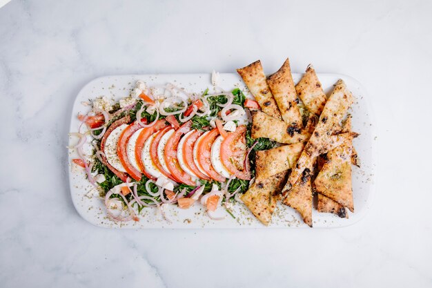 Oven chips with green salad, vegetable and tomato slices.