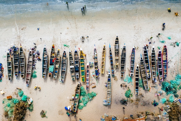 Free Photo overhead aerial shot of different colored boats on a sandy beach with the sea nearby