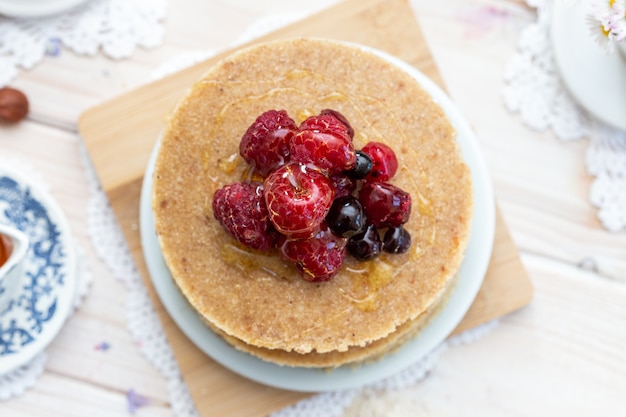 Free photo overhead closeup shot of raw vegan pancakes with honey and berries