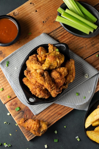 Free photo overhead shot of delicious crispy fried chicken, ketchup and celery sticks on a wooden table