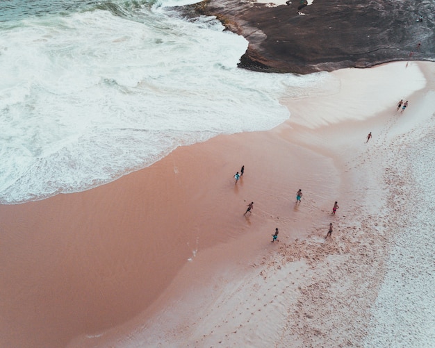 Overhead shot of people enjoying a sunny day at a sandy beach near beautiful waves of the sea