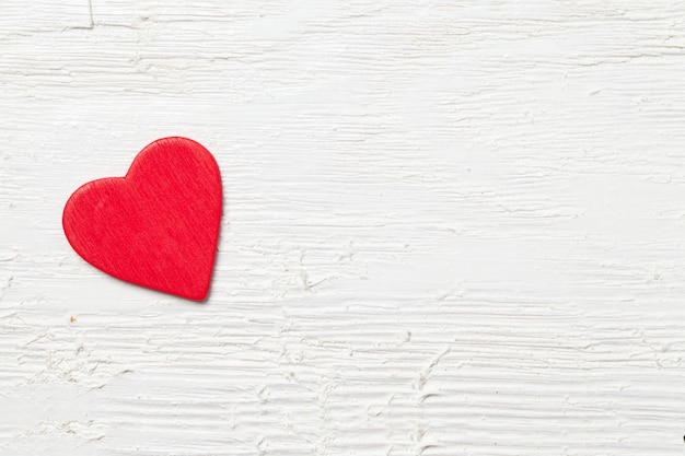 Overhead shot of a small red heart on a white wooden background - romantic concept