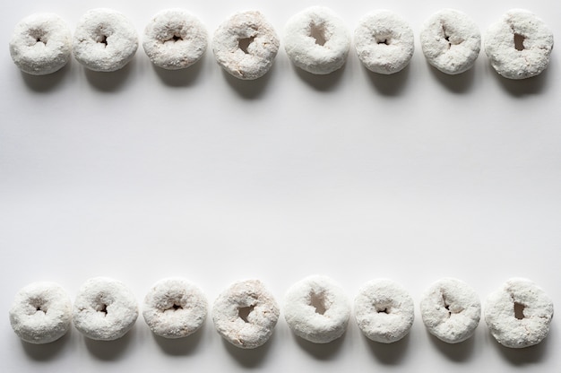 Free photo overhead shot of a white surface with donuts on the top and bottom background