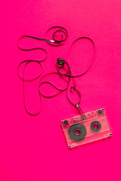 Free Photo an overhead view of audio cassette with tangled tape on pink background