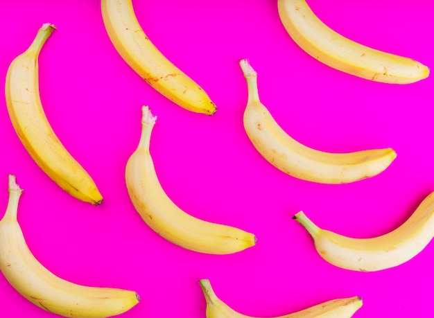 An overhead view of bananas on pink backdrop