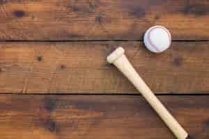 Free photo an overhead view of baseball bat and ball on wooden table