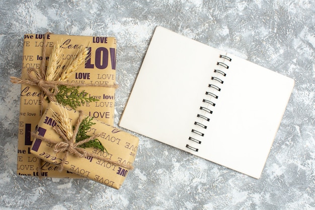 Overhead view of beautiful Christmas packed gifts with love inscription and open notebook on ice table