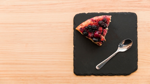 Free Photo overhead view of berry pastry and spoon on shale board