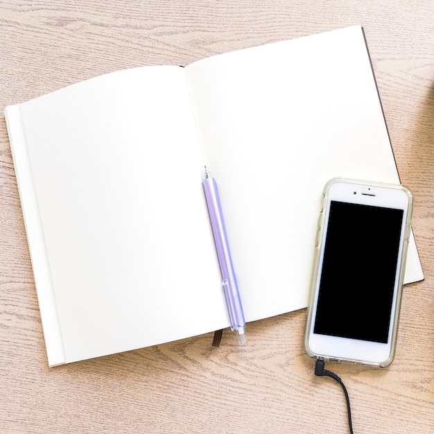 Free photo overhead view of blank paper with pen and cellphone on wooden table