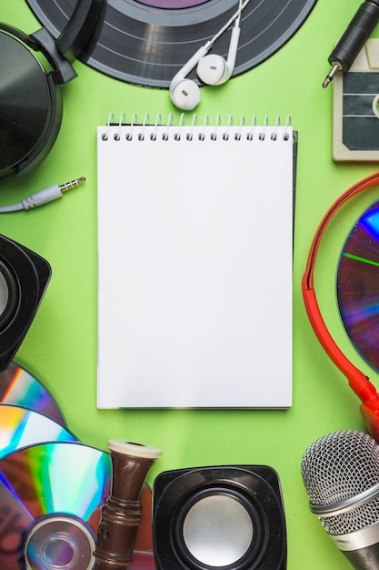 An overhead view of blank spiral notepad with audio equipments