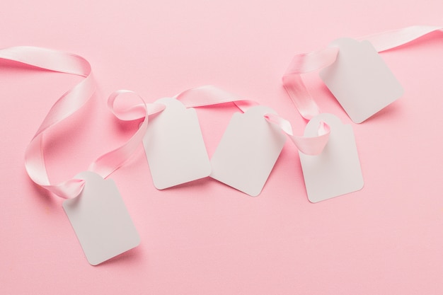 Free Photo overhead view of blank tags and pink ribbon against plain pink backdrop