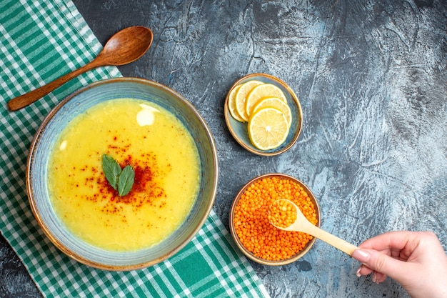 Free photo overhead view a blue pot with tasty soup served with mint and pepper next to chopped lemon wooden spoon and yellow pea on blue background