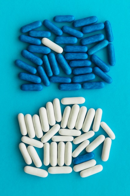 Free photo overhead view of blue and white candy capsules on cyan background