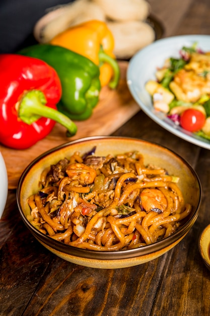 An overhead view of bowl with udon noodles and shrimps on wooden desk