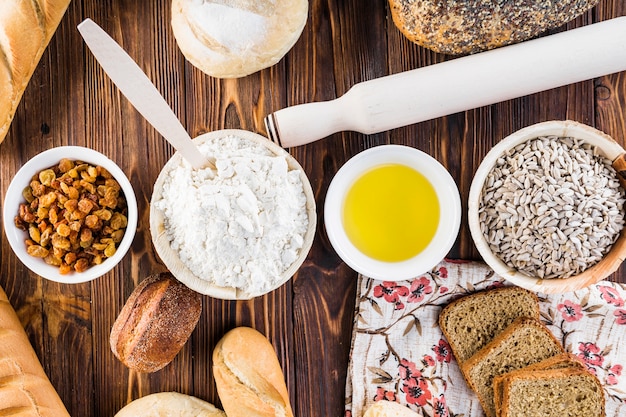 Overhead view of bread bakery ingredients with rolling pin on wooden background