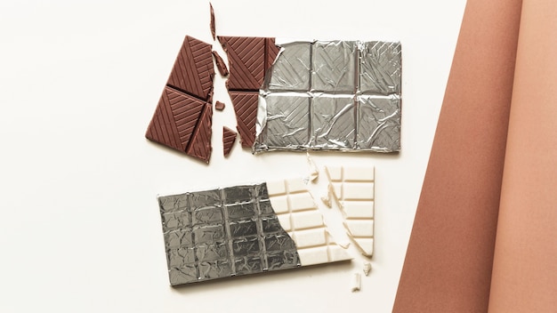 Free photo an overhead view of broken white and brown chocolate bar against white background