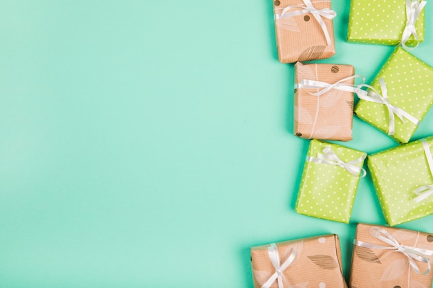 An overhead view of brown and green paper wrapped gift boxes on green backdrop